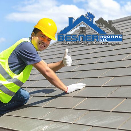 Builder Working On Roof Of New Building, Construction worker wearing safety harness and safety line working on roof new warehouse.