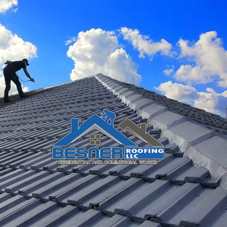 Builder Working On Roof Of New Building, Construction worker wearing safety harness and safety line working on roof new warehouse.